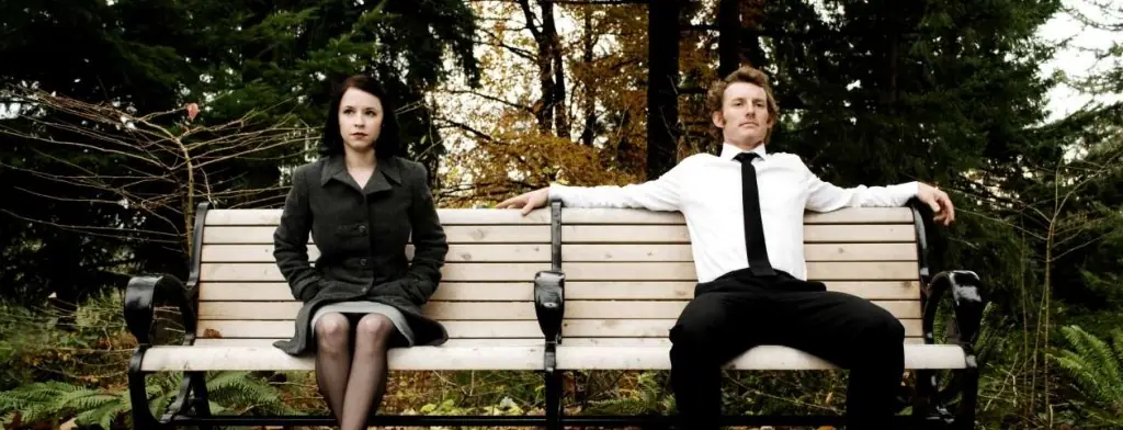 Two people sitting apart on a park bench
