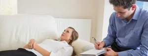 Woman speaking with a therapist while reclining on a sofa