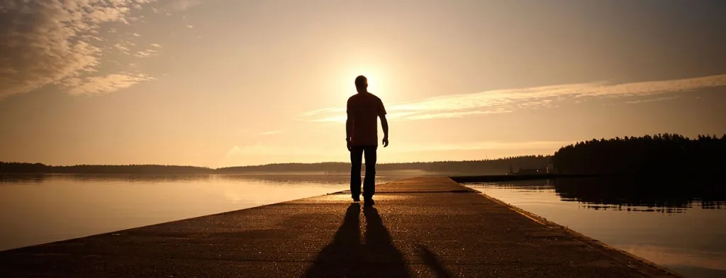Person standing alone on a path at sunset