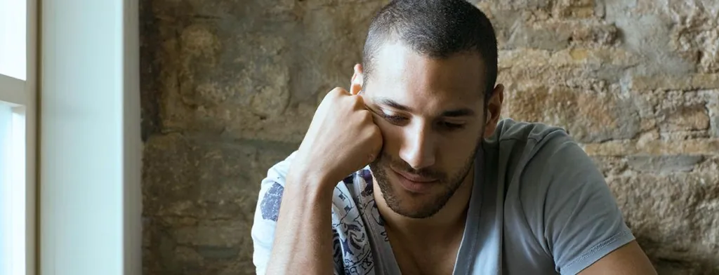 Man sitting with his hand against his face