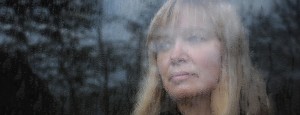 Woman looking out of window with symptoms of depression