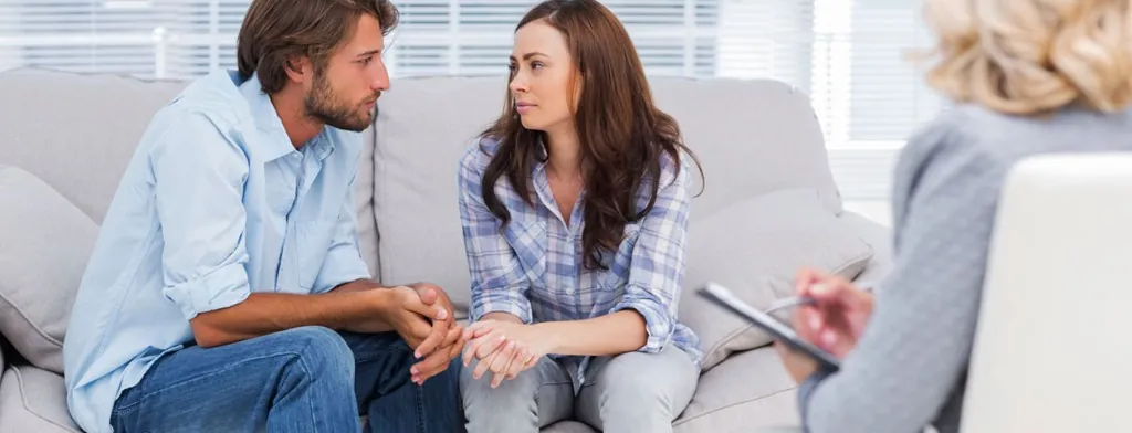 Couple holding hands while speaking with a counselor