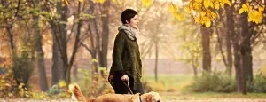 Woman walking a dog in autumn woodland