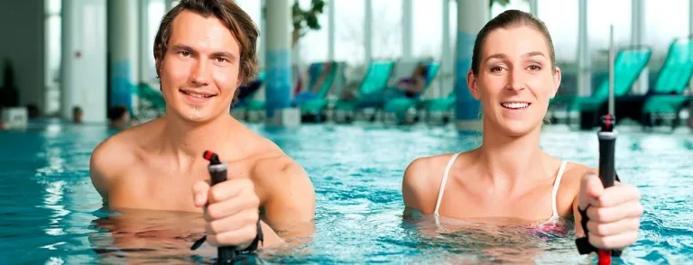 Two people exercising with aquatic resistance equipment in a pool