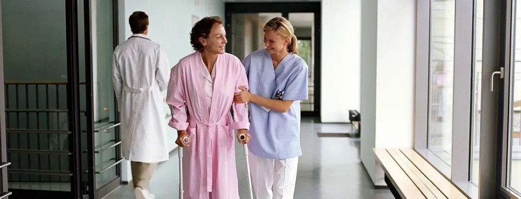 Clinician walking with a person in a hospital corridor