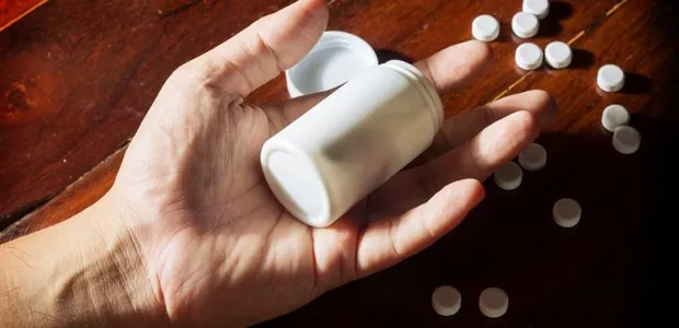 Person tipping tablets out of a bottle
