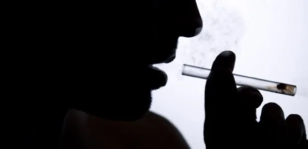 Silhouette of a person holding a glass pipe