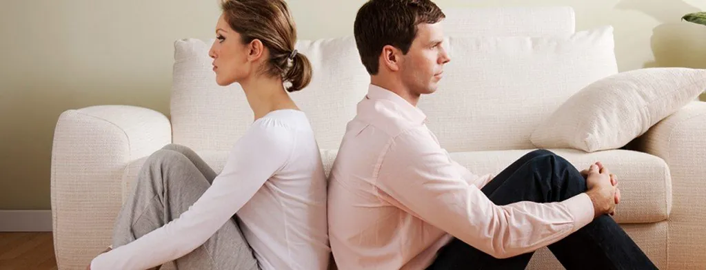 Couple sitting back to back on a sofa
