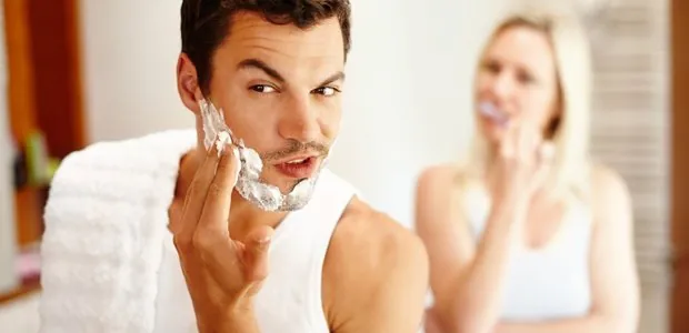 Man shaving while another person looks on