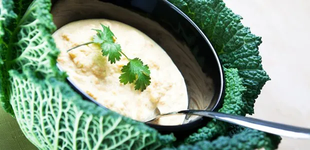 Bowl of soup beside cabbage leaves