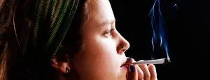 Woman exhaling smoke beside a window