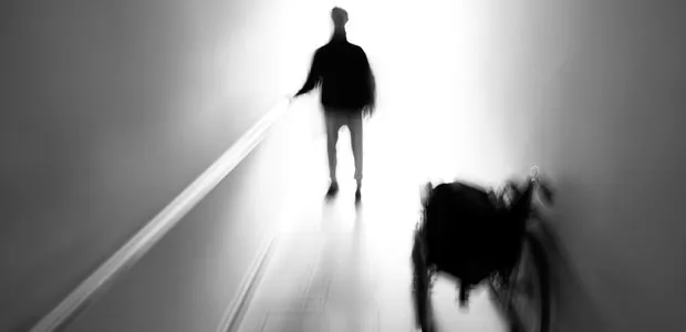 Silhouetted person walking toward a bright doorway