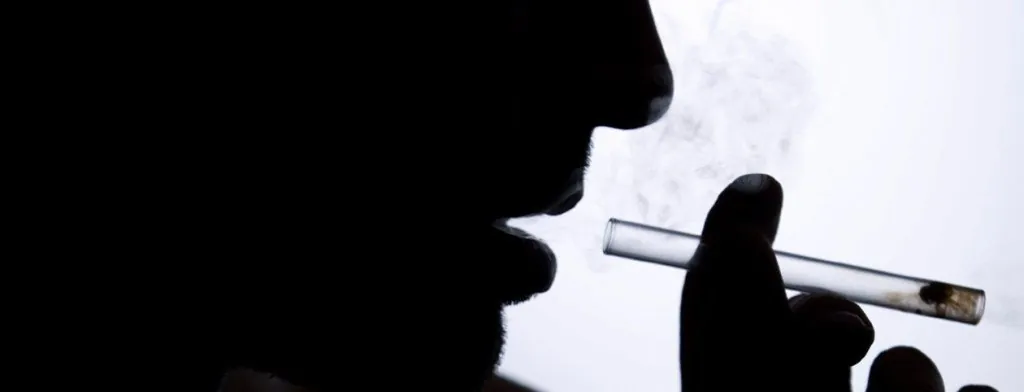 Silhouette of a person holding a glass pipe