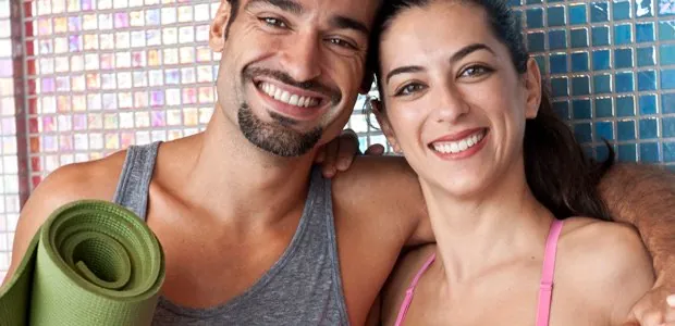 Smiling couple holding exercise mats