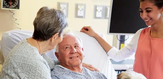 Patient talking with visitors beside a hospital bed