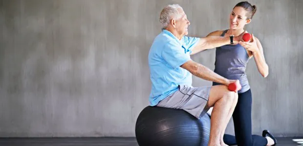 Older man exercising with a small weight and a therapist