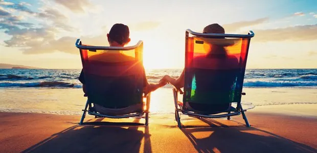 Couple using therapy exercise of taking a trip to improve communication Couple sitting in beach chairs at sunset