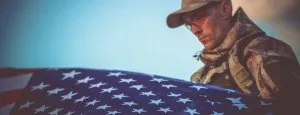 Person in military uniform holding a folded US flag