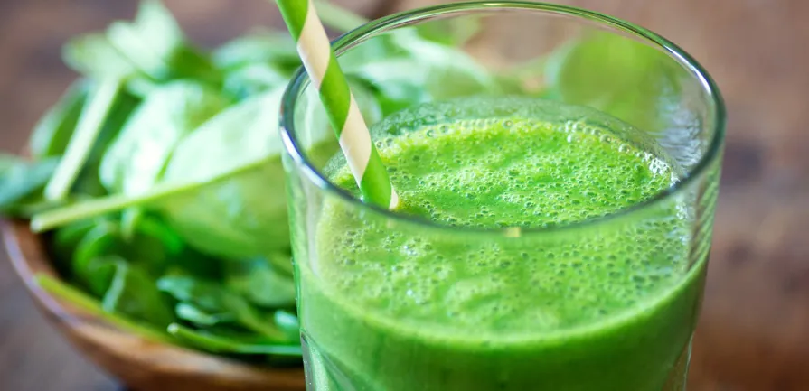 Green smoothie beside spinach leaves