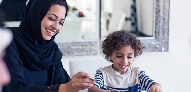 Woman in a headscarf helping a child at a table