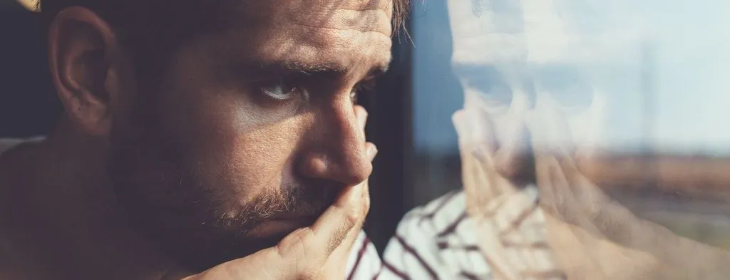 Man looking down while sitting indoors