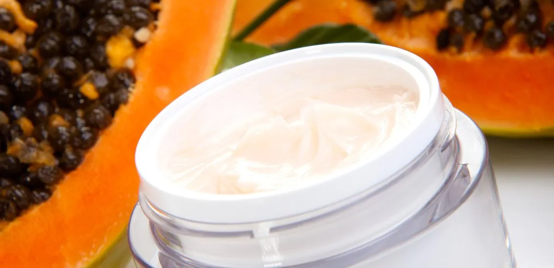 Jar of cream beside cut papaya
