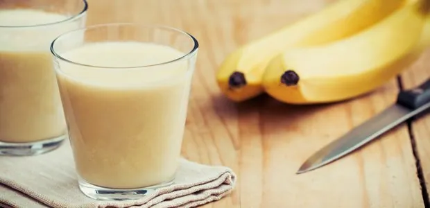 Banana smoothie beside whole bananas