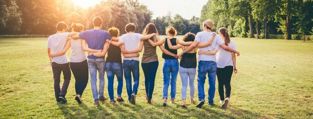 Group standing arm in arm in a grassy field