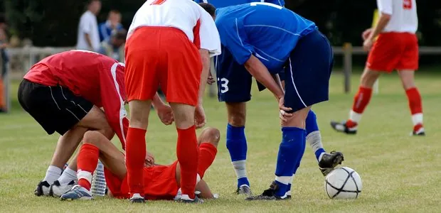 Young soccer players and an adult attending to an injured player
