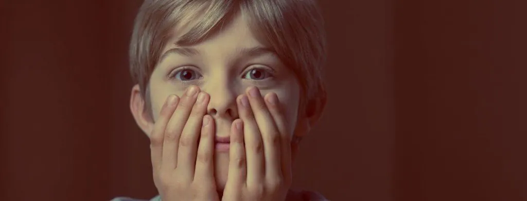 Child holding both hands over their mouth