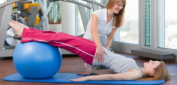 Physical therapist assisting a person exercising with a stability ball