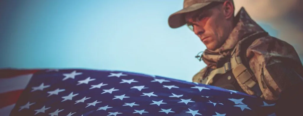 Person in military uniform holding a folded US flag