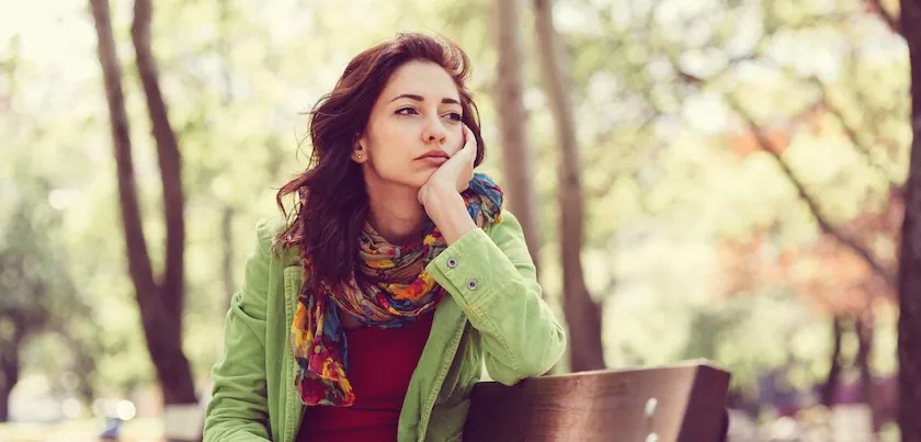 Young woman sitting outdoors with her chin resting on her hand