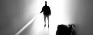 Silhouetted person walking toward a bright doorway
