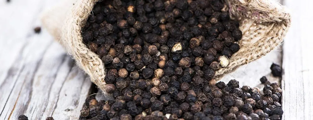 Black peppercorns spilling from a sack