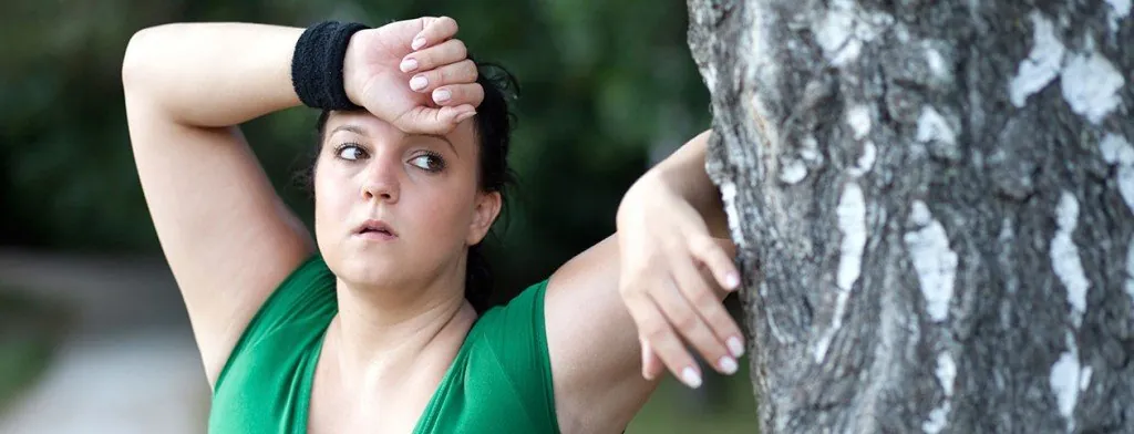 Woman pausing beside a tree during outdoor exercise
