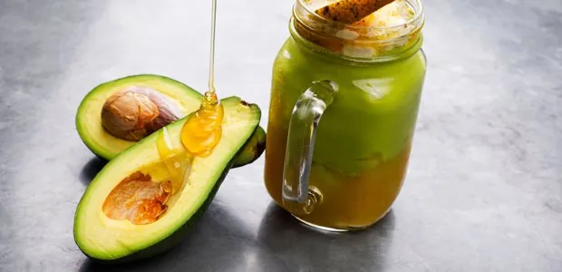Green smoothie beside avocado halves