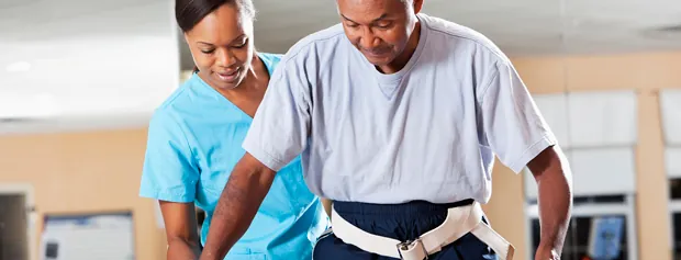 Therapist assisting an older man as he stands