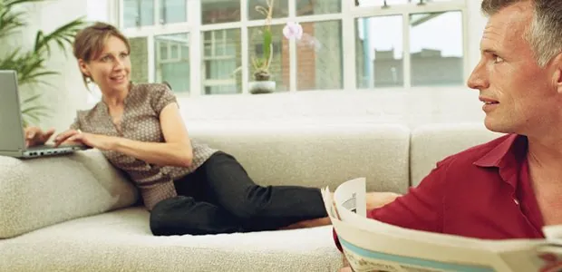 Couple seated at opposite ends of a sofa talking