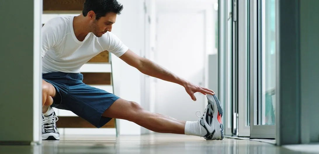 Man stretching his leg at home