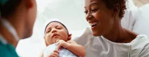 Mother holding a newborn while speaking with a clinician