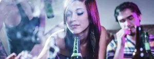 Young woman drinking from a bottle at a social gathering