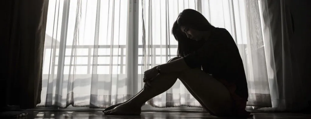 Person sitting in silhouette beside a window
